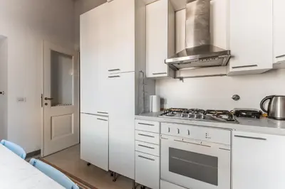 a kitchen with white cabinets and a stove top oven at Appartamento via del Teatro Pace in Rome