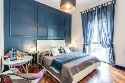a bedroom with blue walls and a bed and a table at Stasera a casa da M.E. in Rome