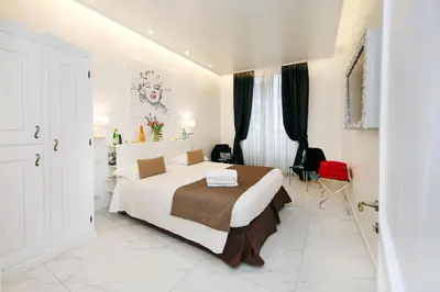 a bedroom with a white bed and a red chair at La Maisonnette Tritone Trevi Apartment Rome in Rome