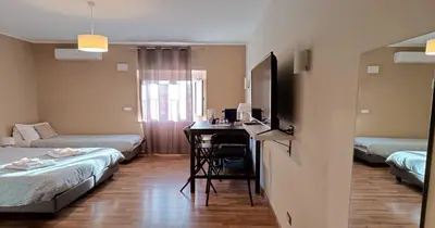a room with two beds and a desk with a television at Rome's Best Holidays Guest House in Rome