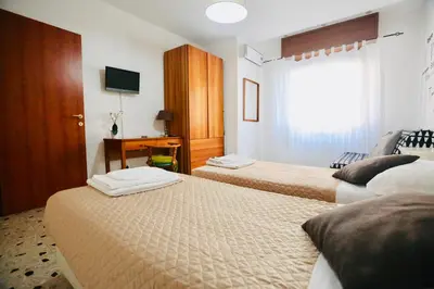 a hotel room with two beds and a desk at Amazing Vaticano in Rome