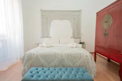 a white bedroom with a bed with a blue ottoman at Snooze Trastevere House in Rome