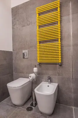 a bathroom with a white toilet and a yellow shutter at Cosy studio in the greenest corner of Trastevere in Rome