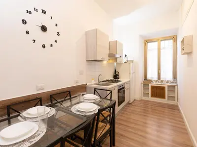 a kitchen with a table and chairs and a clock on the wall at Vatican Apartment Santamaura in Rome