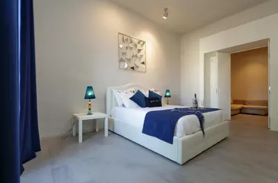 a bedroom with a white bed with a blue comforter at ROMANCE AL COLOSSEO 2 in Rome