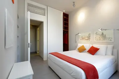 a bedroom with a white bed with red and orange pillows at ROMANCE AL COLOSSEO 2 in Rome
