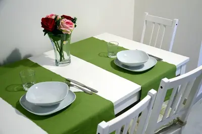 a green table with plates and a vase of flowers at La casa di Egle in Rome