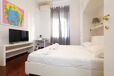 a white bedroom with a bed and a television at LC GrandTour Libertà in Rome