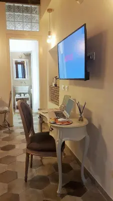 a desk with a laptop and a television on a wall at Colosseo Sweet Home in Rome