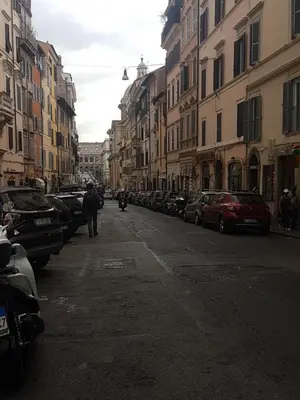 a person walking down a street with parked cars at Colosseo Sweet Home in Rome