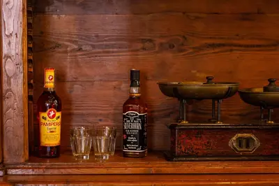two bottles of alcohol and glasses on a wooden shelf at The Dreamers House in Rome