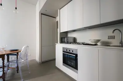 a kitchen with white cabinets and a table and a stove at Casa Satrico in Rome