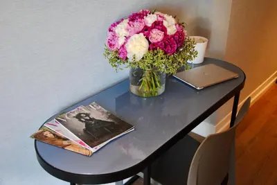 a vase of flowers on a table with a laptop at Hotel St Martin by OMNIA hotels in Rome