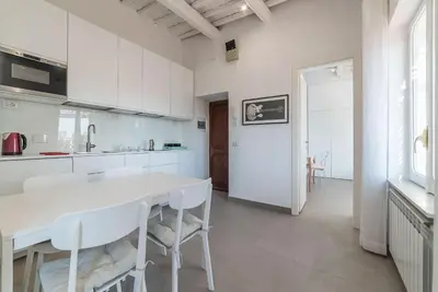 a white kitchen with a white table and chairs at GuestHost - Piazza Navona Panoramic Penthouse in Rome