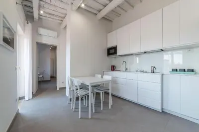 a kitchen with white cabinets and a table and chairs at GuestHost - Piazza Navona Panoramic Penthouse in Rome