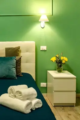a green bedroom with a bed and a vase of flowers at Lydka Domus in Rome