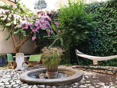 a garden with a fountain with flowers and a hammock at Vatican Fairytale Garden in Rome