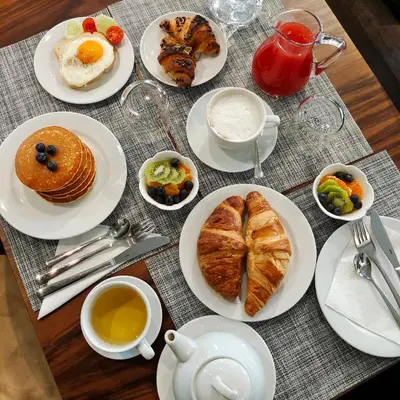 a table with plates of breakfast food and cups of coffee at Ada Home in Rome