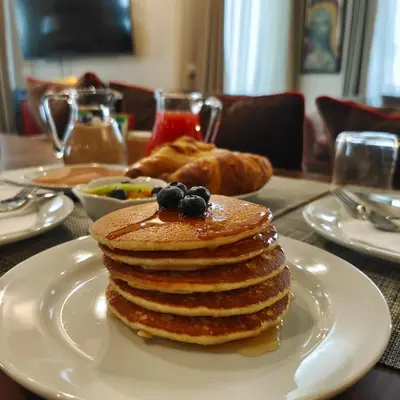 a stack of pancakes on a white plate on a table at Ada Home in Rome