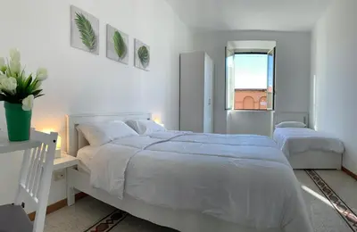 a white bedroom with two beds and a window at Chiaretta Guest House in Rome