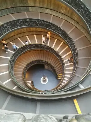 a spiral staircase in a building with people walking down it at Chiaretta Guest House in Rome