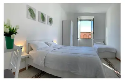 a white bedroom with two beds and a window at Chiaretta Guest House in Rome