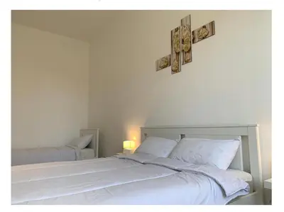 a bedroom with two white beds and a cross on the wall at Chiaretta Guest House in Rome