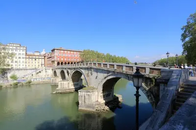 a stone bridge over a river in a city at Welcome to Trastevere in Rome