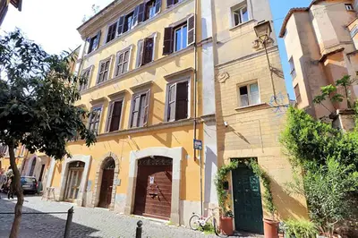 a large yellow building with a green door on a street at Welcome to Trastevere in Rome