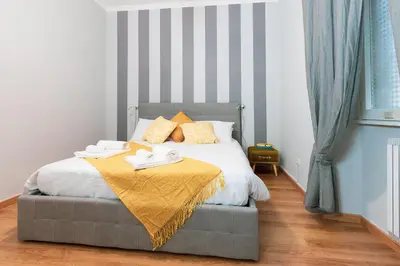 a bedroom with a bed with a yellow blanket on it at Relais Mantellini in Rome