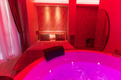 a bathroom with a large pink tub in front of a bed at Silver Suite Coliseum in Rome