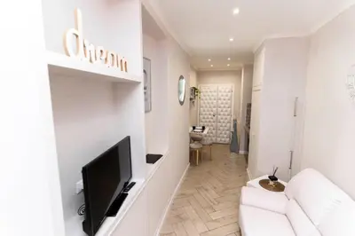 a white living room with a white couch and a television at Silver Suite Coliseum in Rome