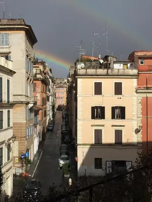 a rainbow over a city street with buildings at Center House Colosseo in Rome