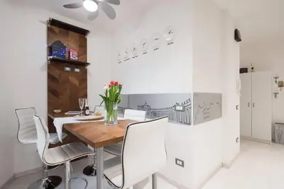 a dining room with a wooden table and white chairs at RomeEyes apartment in Rome