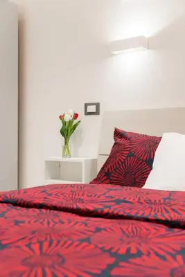 a bed with a red comforter and a vase with flowers at RomeEyes apartment in Rome