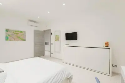 a white bedroom with a bed and a flat screen tv at RomeEyes apartment in Rome