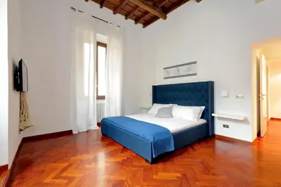 a blue bed in a white room with a wooden floor at Campo dei Fiori Giubbonari Amazing in Rome