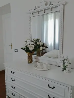 a dresser with a mirror and a vase of flowers on it at Glory House Trastevere in Rome