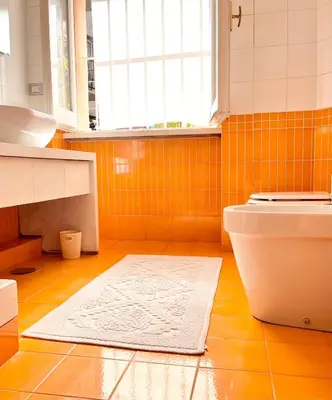 an orange tiled bathroom with a toilet and a sink at Glory House Trastevere in Rome