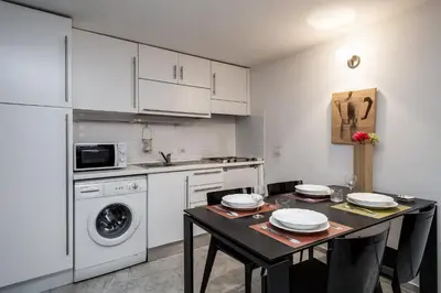 a kitchen with white cabinets and a table with chairs at Rome Loft in Rome