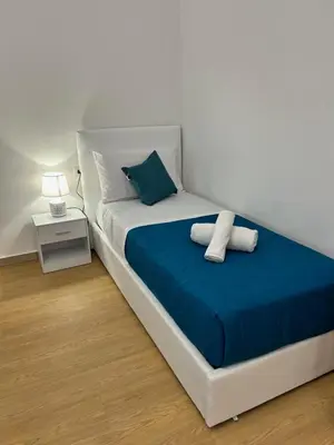 a white bed with blue sheets and pillows on it at San Peter Vale House in Rome
