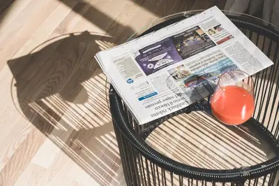 a newspaper and a glass of juice on a bench at The Vista Rooms & Terrace in Rome