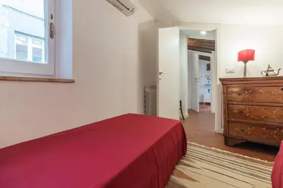 a bedroom with a red bed and a dresser at Three bedrooms in world-famous Via Giulia - FromHometoRome in Rome