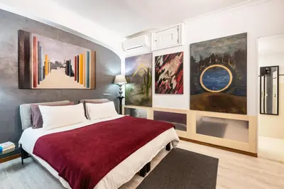 a bedroom with a large bed with paintings on the wall at Spanish Steps Art Gallery- Roma in Rome