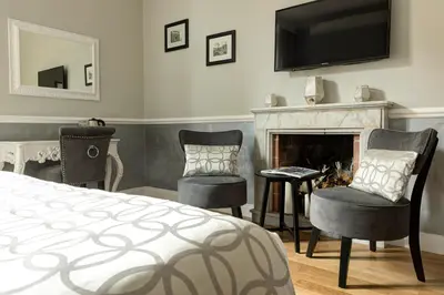 a bedroom with a bed and two chairs and a fireplace at Relais de l'Opera Luxury Rooms in Rome