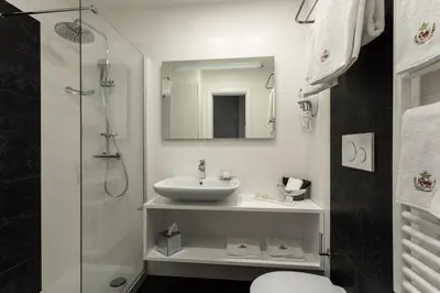 a white bathroom with a sink and a shower at Relais de l'Opera Luxury Rooms in Rome