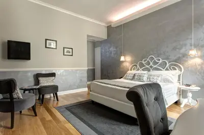 a bedroom with a white bed and a gray wall at Relais de l'Opera Luxury Rooms in Rome
