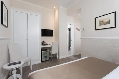 a white room with a bed and a desk at Relais de l'Opera Suites in Rome
