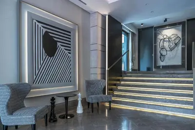 a lobby with stairs and chairs and a painting at The Regency, Rome, a Tribute Portfolio Hotel in Rome