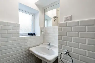 a white bathroom with a sink and a mirror at Trevi Fountain Stylish Penthouse IREX Apartment in Rome